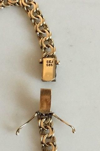 Närbild på låset till ett bismarckhalsband i guld med stämplar.